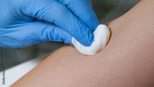 A healthcare professional applies antiseptic to a patient's arm before a procedure to ensure safety.