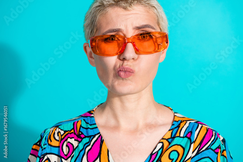 Canvas Print Stylish young woman in vibrant glasses pouting against a teal backdrop