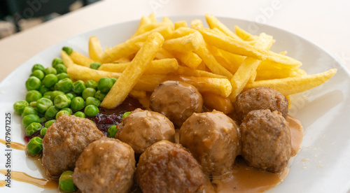Meatballs with french fries, green peas, bechamel sauce and cranberry jam