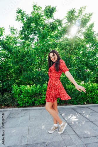 women in a red polka dot dress smiling on the street