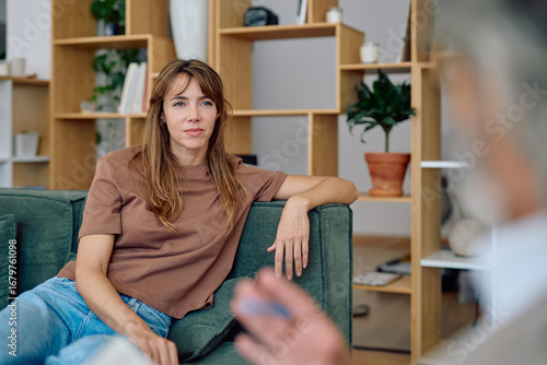 Foto Young woman sitting comfortably on a sofa, engaging in a meaningful conversation