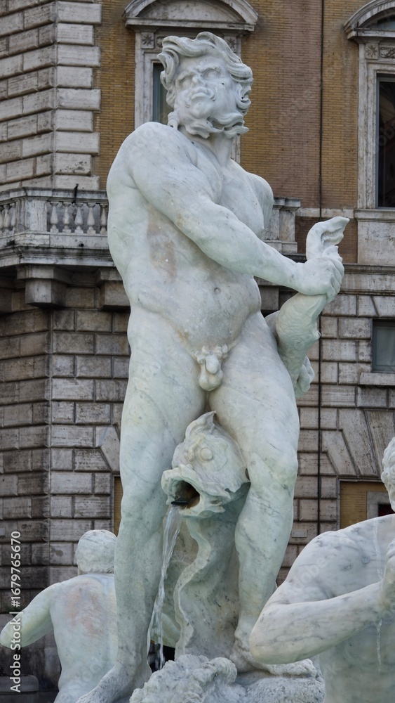 Obraz premium Rome, Italy - 10 January 2025. A powerful male statue at Piazza Navona holds a sea creature as water flows from a fish at his feet in the Fontana del Moro.
