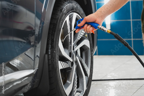 Obraz na płótnie At an auto detailing garage, a mechanic cleans and dries a vehicle's wheel with an air compressor and air nozzle