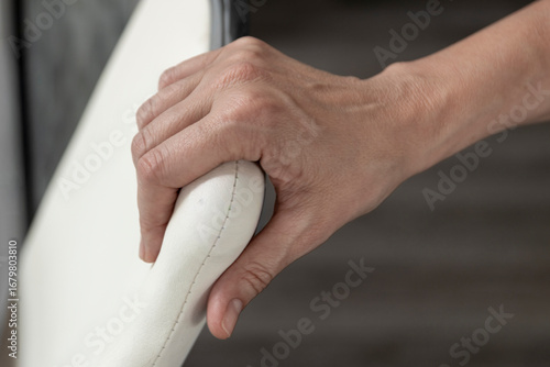 Hand gripping white leather armrest of modern chair