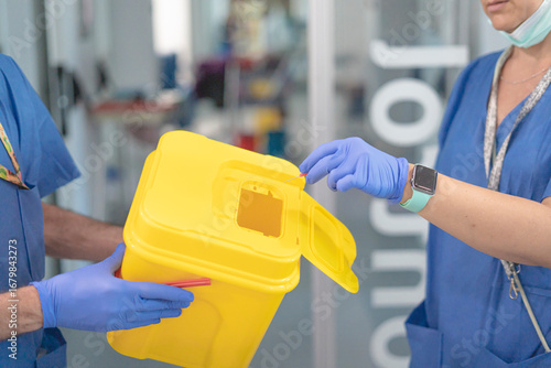 Schilderij op canvas Two healthcare professionals disposing of medical waste in sharps container