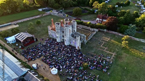aerial wide mid angle drone shot panning left tracking ancient old English ruins Titchfield abbey in countryside with large crowd of people in summer at sunset