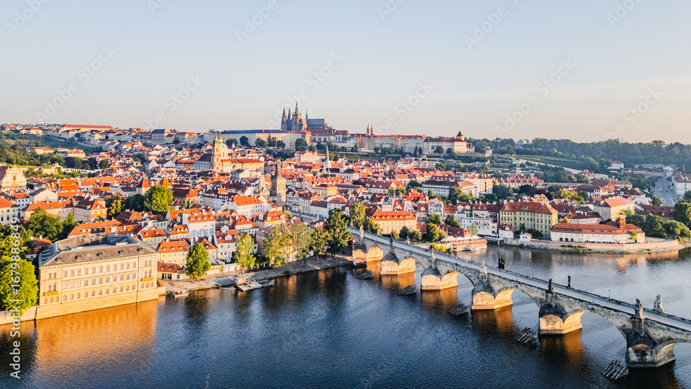 Obraz premium The sun rises over Prague, illuminating the medieval architecture and the Vltava River. The Charles Bridge bridges the gap between the city's past and present, creating a breathtaking panorama.