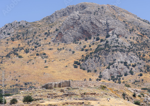 Ancient Mycenean walls as seen from a distance in a barren landscape