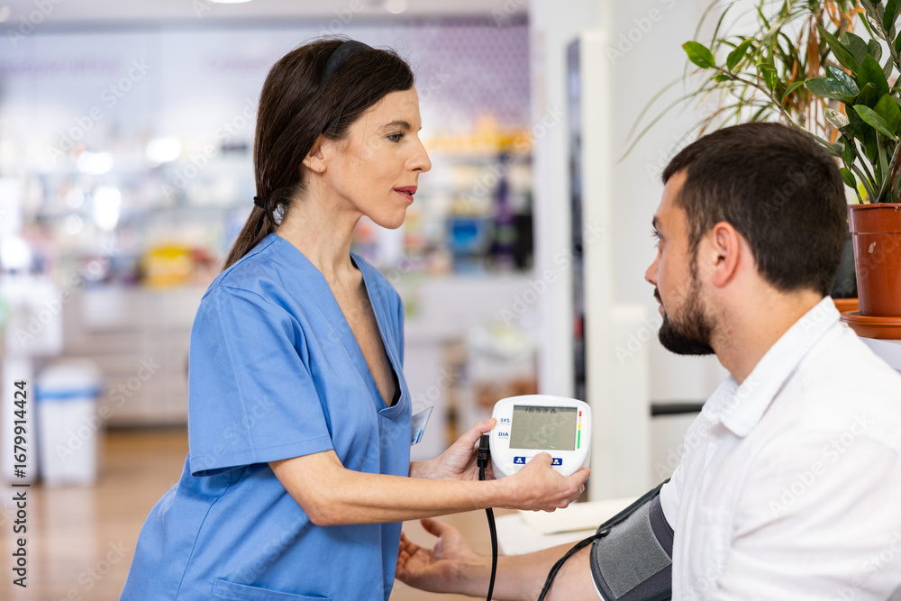 Obraz premium Pharmacist measures arterial blood pressure with a tonometer in a man