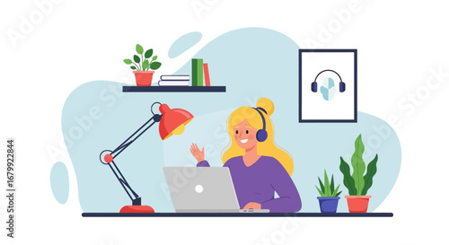 Happy woman in headphones waves during a video call on her laptop, illustrating remote work, online learning, or virtual communication from a cozy home office.