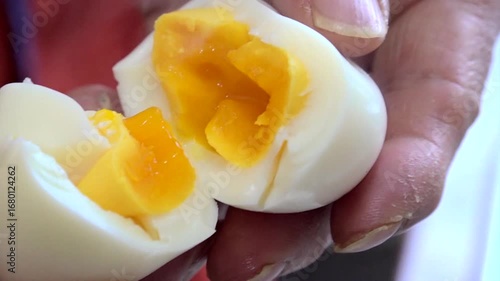 A hand holding a soft-boiled egg