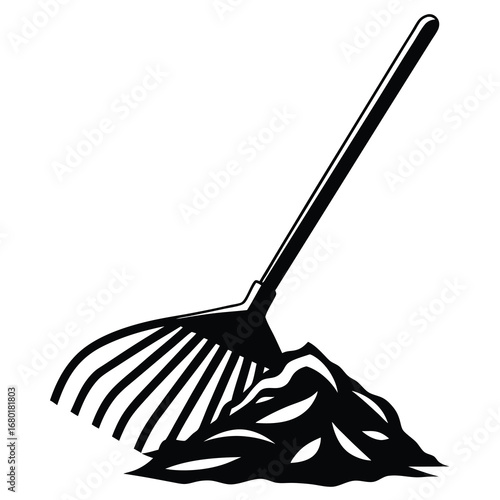 Black and white image of a rake and a pile of leaves