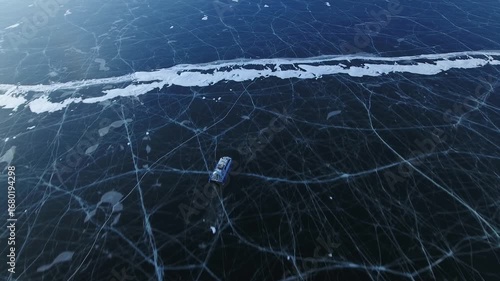 Epic aerial above air-cushion vehicle speeding on winter frozen lake icy expanse with dramatic fractures. Conquering new places through extreme tourism at Siberia's UNESCO world heritage destination