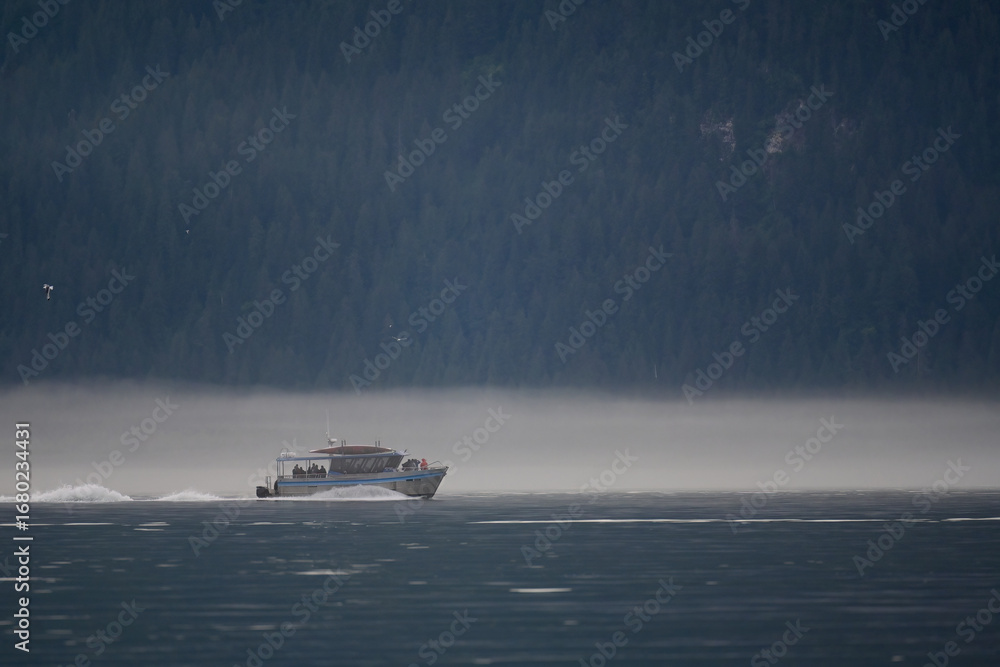 Fototapeta premium Tourists head out of Seward, Alaska, on a foggy morning for a day of sightseeing and wildlife watching in Resurrection Bay.