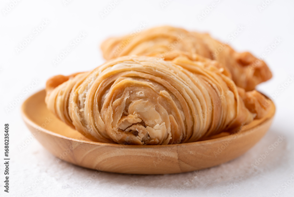 Fototapeta premium Curry puff stuffed with chicken or sweet potatoes on wooden plate with white background, Thai snack food style