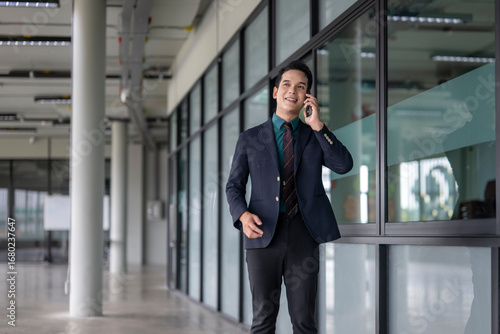 Wallpaper Mural Asian businessman walking and talking on phone in office hallway Torontodigital.ca