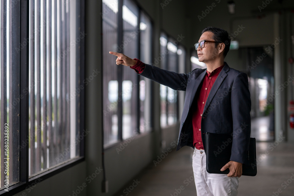 Fototapeta premium Architect pointing at new building project through window
