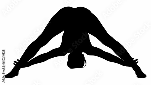 Silhouette of woman in wide legged forward bend yoga pose with arms extended reaching for feet pose