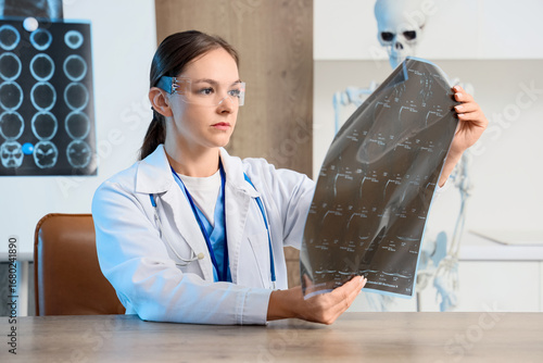 Female doctor in lab coat and futuristic glasses examining medical x-ray scan...