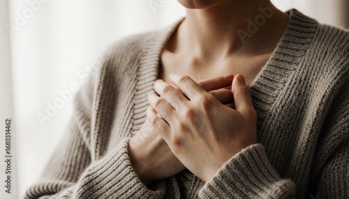 A woman's hands gently clasped over her chest, conveying comfort and self-reflection.