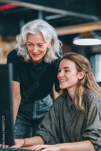 A mentoring session where an older manager coaches a younger employee at a desk