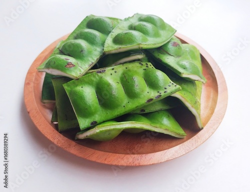 Obraz na płótnie Raw Petai (Parkia Speciosa) or Bitter Bean in a wooden plate on a white background