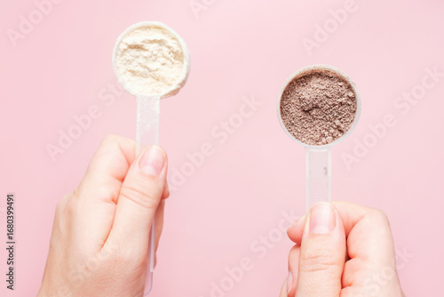 Female hands holding protein powder close-up top view on pink background.