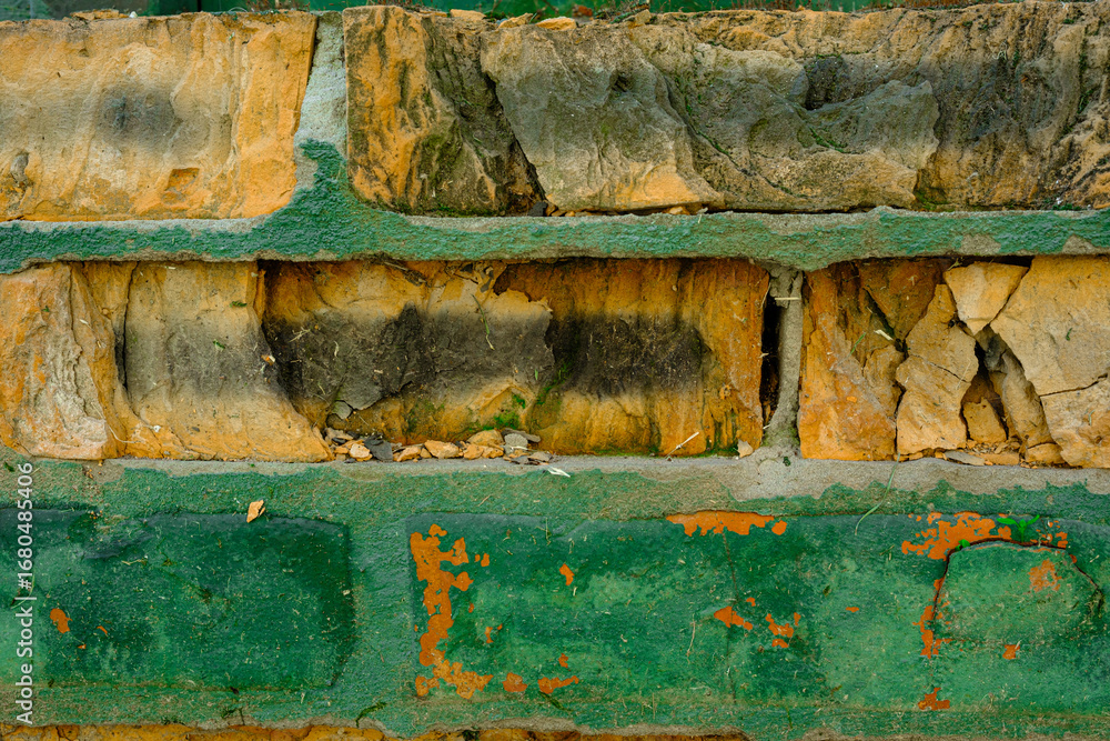 Fototapeta premium Close up of damaged brick wall with peeling green paint for weathered architecture concept