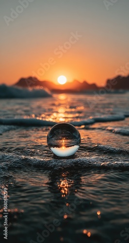 Crystal ball reflecting sunset over ocean waves