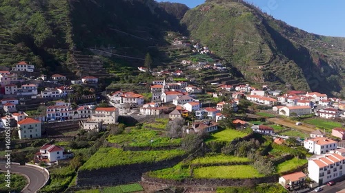 Aerial Drone Shot Circling Church and Coastal Town on Lush Green Cliffside in Porto Moniz, Madeira, Portugal.