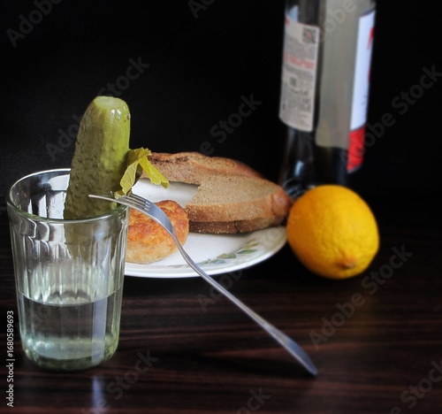 A glass of Russian vodka and a pickled cucumber on a fork.