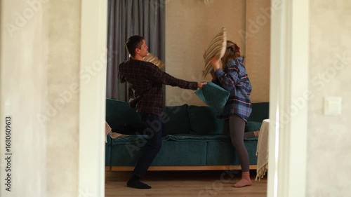 A young couple engages in a lighthearted pillow fight, filled with laughter and playful antics. Experience the joy of love and play as they enjoy each others company in a cozy and playful environment