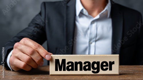 Person in Black Suit Placing Manager Block on Wooden Desk
