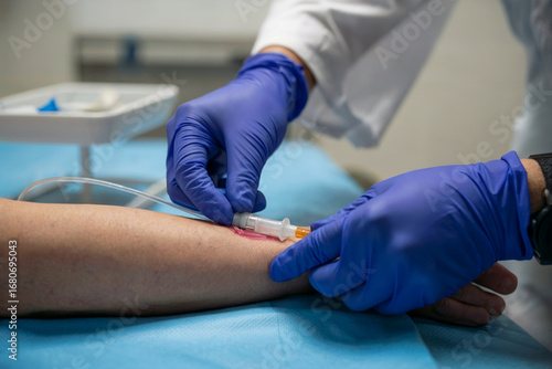 Close up of medical professional inserting I V catheter into patient arm IV insertion intravenous