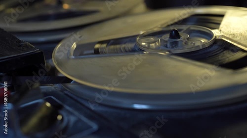 Vintage professional analog reel to reel tape recorder on black studio background.