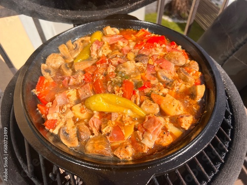 Beef meat and vegetables stew in black bowl with roasted baby potatoes. Dark background grill kamado bbq.