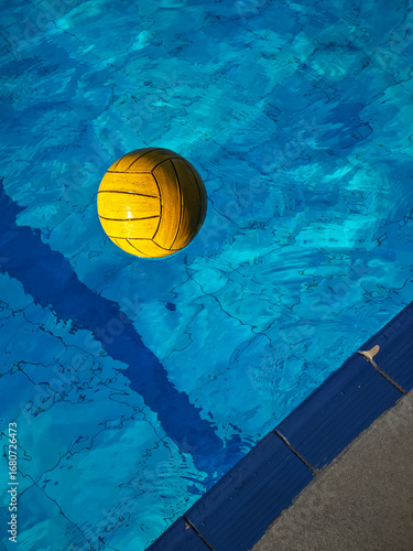 Yellow waterpolo ball on the surface of the water