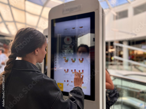 Close-up of teenager paying for takeaway food using mobile phone contactless payment at self-service kiosk. Concept: cashless payments, modern technology, digital everyday life.