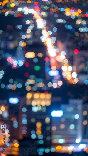 A nighttime cityscape panorama displays a bokeh effect from illuminated buildings and roadways.