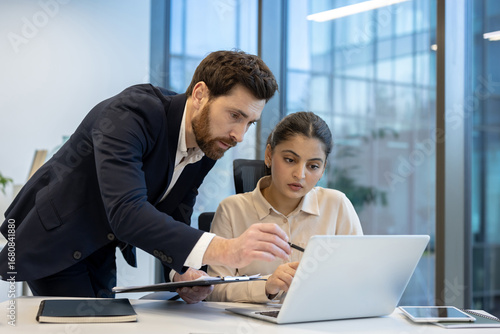 Business colleagues collaborating on laptop in modern office