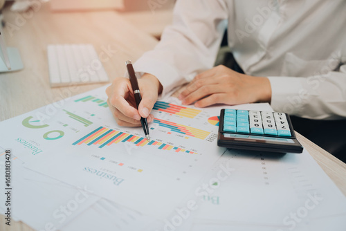 Detailed Analysis of Business Performance with Data Charts and Calculators in Modern Office Setting