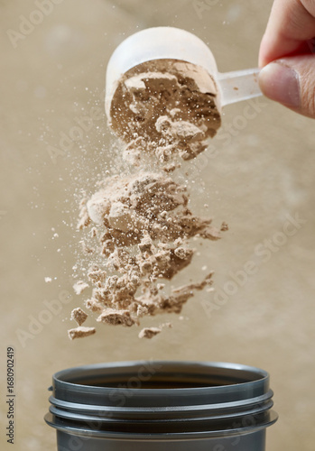 protein powder spills in cup from measure scoop.  whey sports nutrition. dry mixture