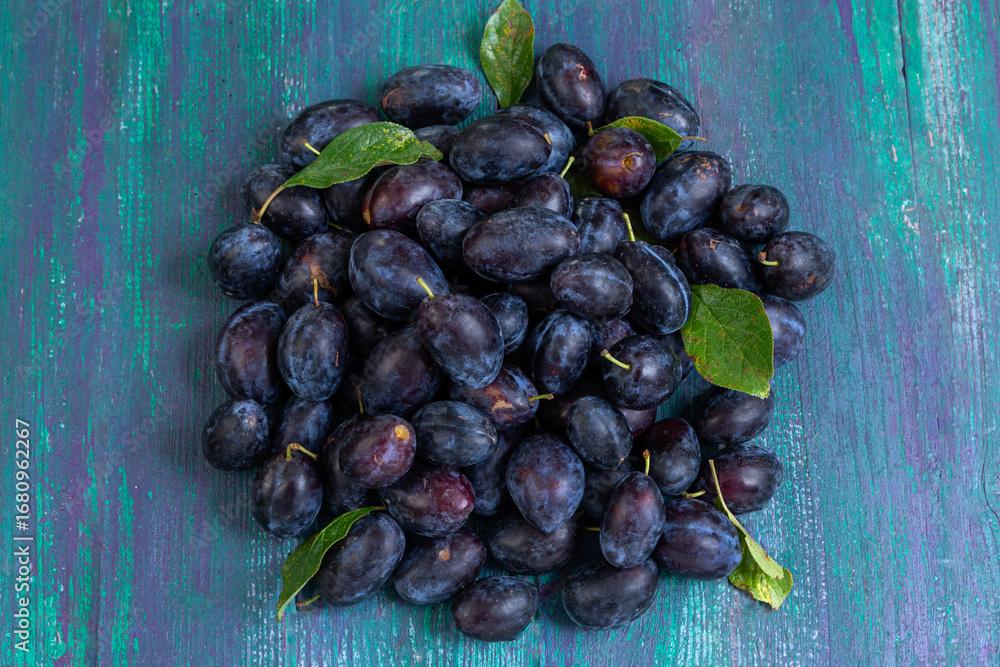 Fototapeta premium Fresh plums gathered on a rustic wooden surface