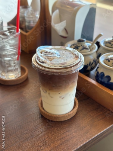An inviting 45-degree angle shot of a vibrant Iced Caramel Macchiato in a clear glass, beautifully highlighting the layered textures and sweet caramel drizzle on a wooden cafe table.