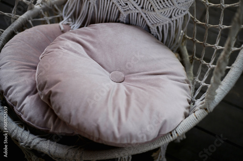 The swing is light wicker with a soft pillow in the style of macrome. Boho style, garden design.