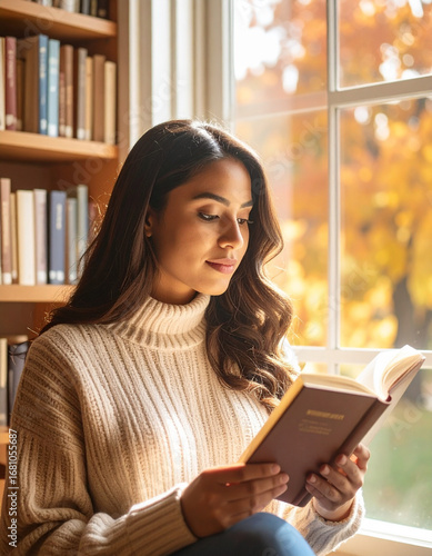 Young woman reading a book by the window in library, autumn trees outside, warm light, cozy intellectual atmosphere, realistic lifestyle photo
