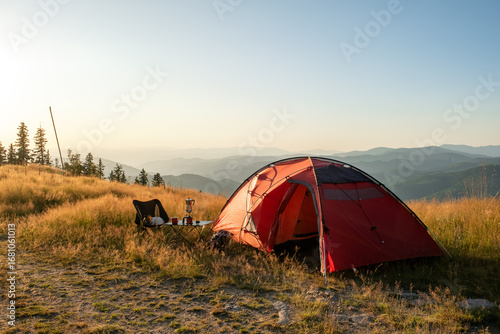 Fototapeta Naklejka Na Ścianę i Meble -  Summer Pamporovo Bulgaria aerial sunset view, red tent glowing on mountain meadow, golden light across hills, outdoor adventure travel destination in Balkan mountains, serene tourism nature scene.