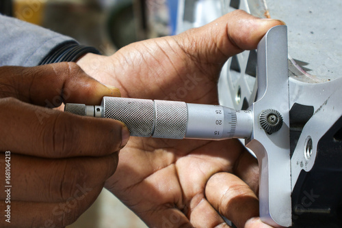 Картината върху платно Close-up shot of a person's hands using a depth micrometer to precisely measure a large industrial metal component