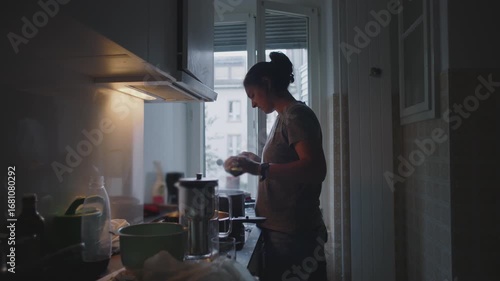 Mother cooking dinner in kitchen while holding toddler nearby, stirring pot on stove during busy evening family routine in cozy home atmosphere