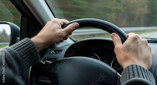 Close-up of hands firmly holding steering wheel in a vehicle. Surrounding scenery features blurred trees and calm road, suggesting a serene autumn drive